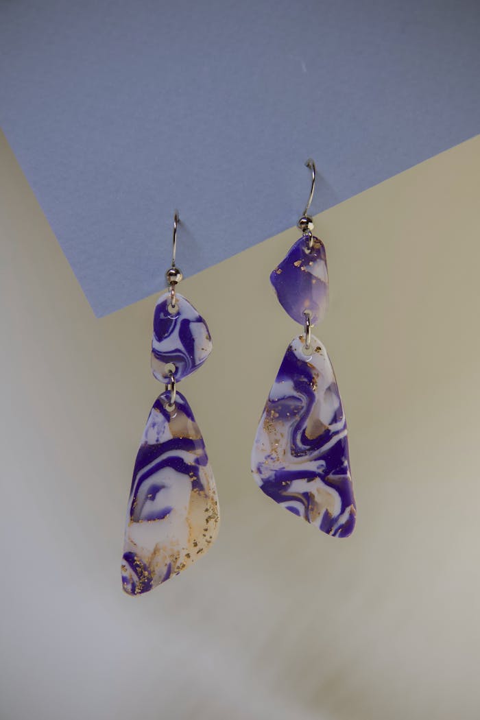 hero-img-01 Close-up of unique purple marbled earrings in an artistic and fashion-forward style.